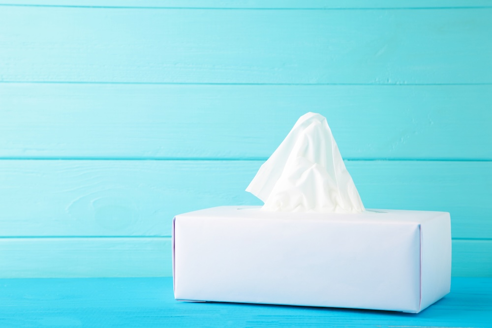 Box with paper tissues on blue background. Top view